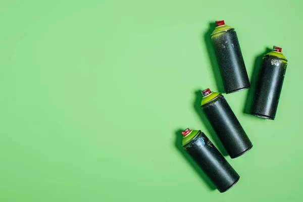 Top view of arranged cans with aerosol paint isolated on green — Stock Photo