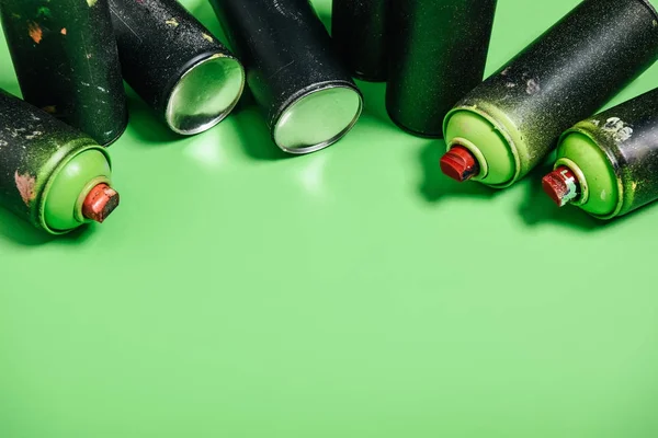 Close up view of arranged cans with aerosol paint isolated on green — Stock Photo