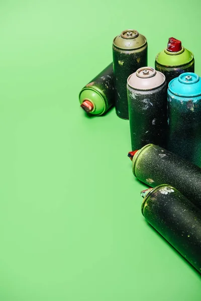 Close up view of arranged cans with aerosol paint isolated on green — Stock Photo