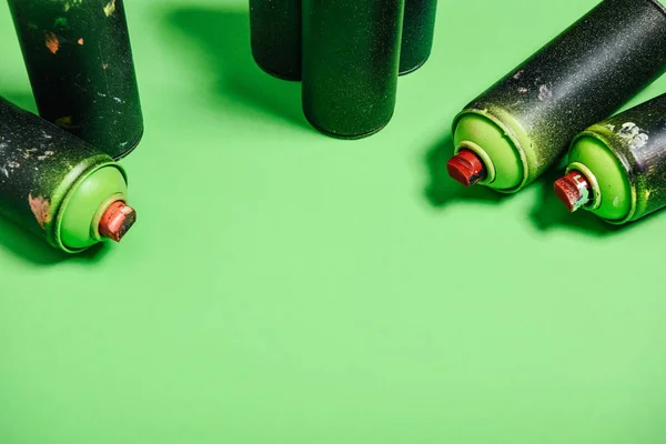 Close up view of arranged cans with aerosol paint isolated on green — Stock Photo