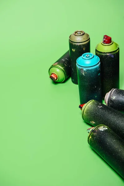 Close up view of arranged cans with aerosol paint isolated on green — Stock Photo