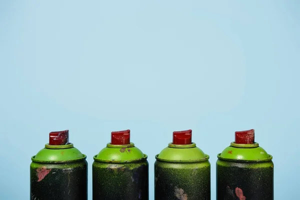 Vista de perto de latas dispostas com tinta aerossol isolado em azul — Fotografia de Stock