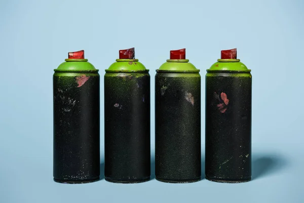 Vista de perto de latas dispostas com tinta aerossol isolado em azul — Fotografia de Stock