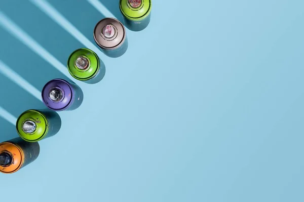 Top view of arranged cans with aerosol paint isolated on blue — Stock Photo
