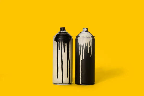 Vista de perto de tinta aerossol preto e branco em latas isoladas em amarelo — Fotografia de Stock