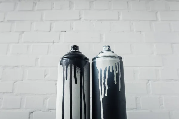 Vista de cerca de pintura en aerosol en latas con fondo de pared de ladrillo - foto de stock