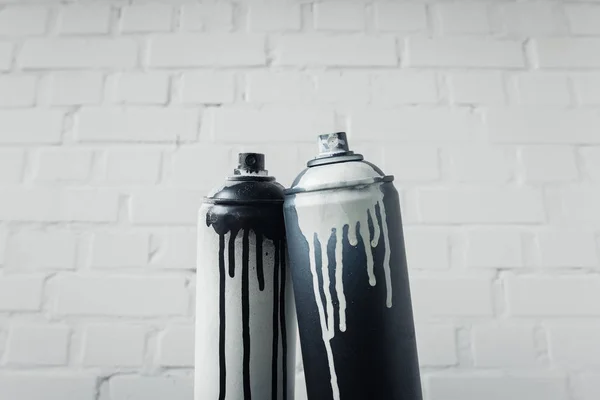 Close up view of spray paint in cans with brick wall background — Stock Photo