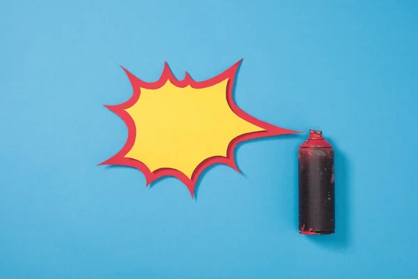 Vue du dessus de la peinture en aérosol dans la boîte et bulle de discours en papier vide isolé sur bleu — Photo de stock