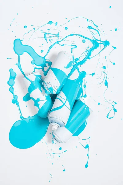 Vista de cerca de pintura en aerosol en latas cubiertas con pintura azul aislada en blanco - foto de stock