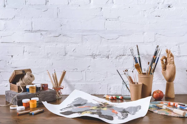 Boceto y copas con pinceles sobre mesa de madera en taller — Stock Photo