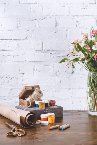 Bouquet de fleurs et affiche peintures sur table en bois — Photo de stock