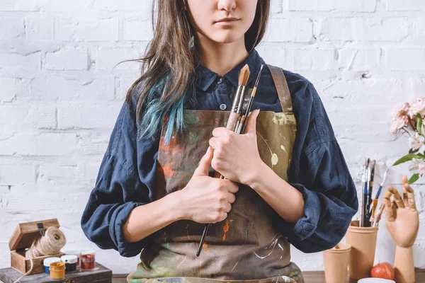 Cropped image of female artist holding brushes — Stock Photo