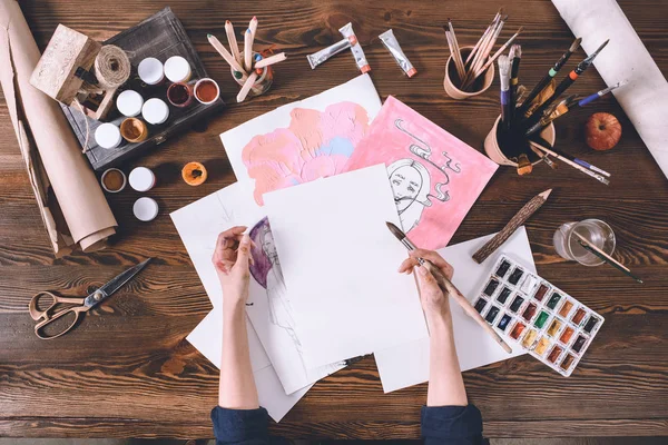 Recortado tiro de artista femenina pintura bocetos en el lugar de trabajo con pinturas y pinceles — Stock Photo