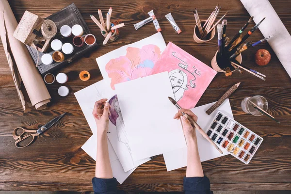 Recortado tiro de artista femenina pintura bocetos en el lugar de trabajo con pinturas y pinceles - foto de stock