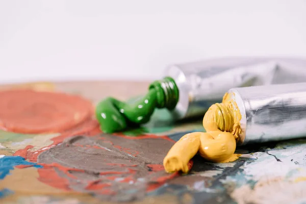 Close-up view of palette with colorful paints in tubes — Stock Photo