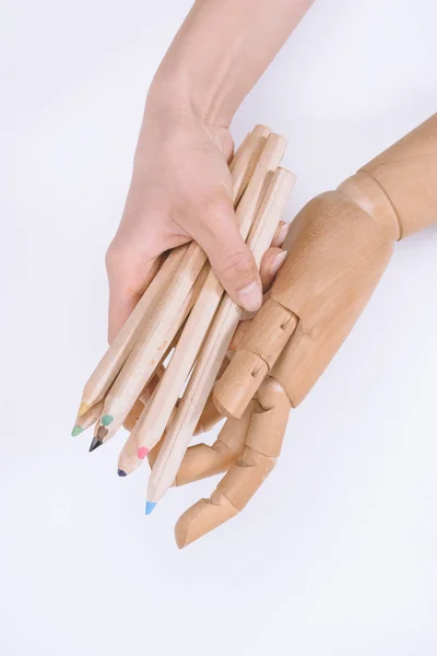 Cropped shot of human hand and dummy holding crayons isolated on white — Stock Photo