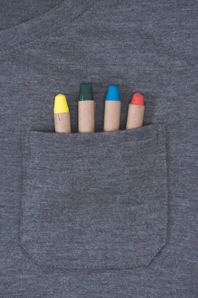 Close-up view of grey male t-shirt with colorful crayons in pocket — Stock Photo