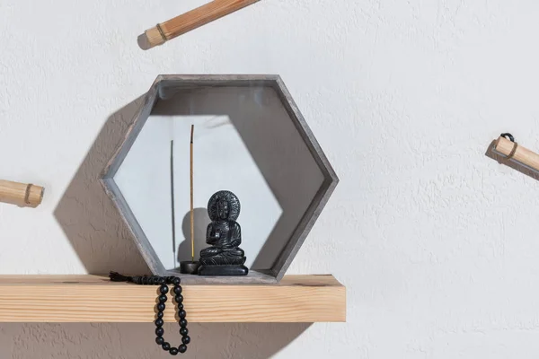 Small statue of buddha in frame and rosary on wooden shelf — Stock Photo