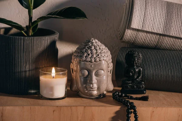 Sculptures de bouddha et tapis de yoga sur étagère en bois — Photo de stock