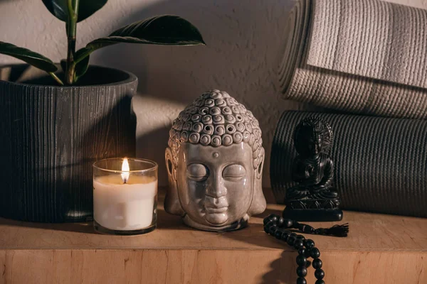 Esculturas de buddha y colchonetas de yoga en estante de madera — Stock Photo