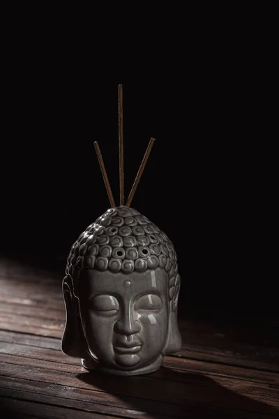 Sculpture of buddha head with incense sticks — Stock Photo