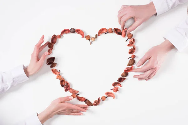 Imagen recortada de pareja haciendo corazón de frutos secos en día de San Valentín aislado en blanco - foto de stock