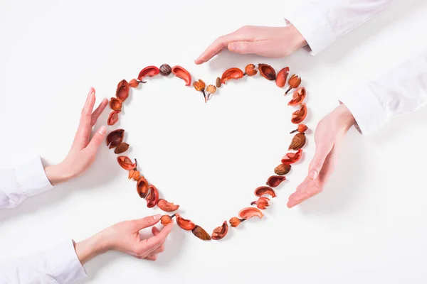 Imagen recortada de pareja haciendo corazón de frutos secos en el día de San Valentín en blanco - foto de stock