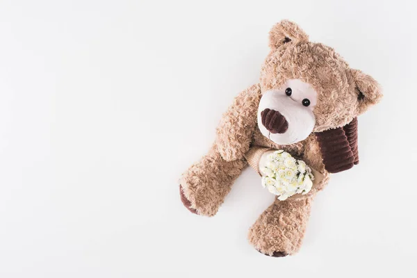 Vista superior del osito de peluche con ramo de flores blancas aisladas en blanco - foto de stock