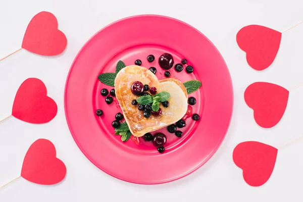 Draufsicht auf herzförmigen Pfannkuchen und Papierherzen isoliert auf weißem, Valentinstag-Konzept — Stockfoto