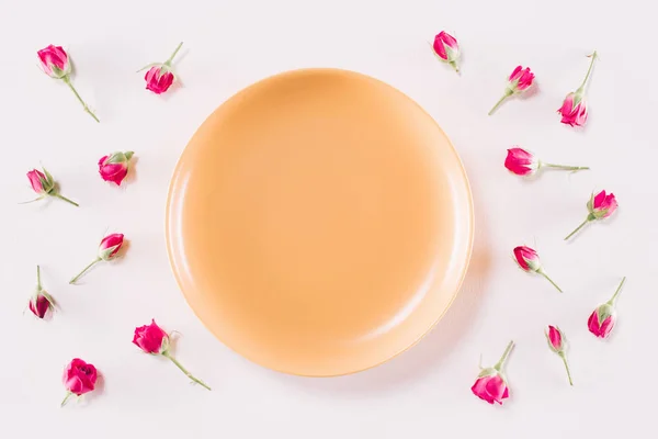 Vue du dessus de la plaque jaune et des roses éparses isolées sur blanc, concept de Saint-Valentin — Photo de stock