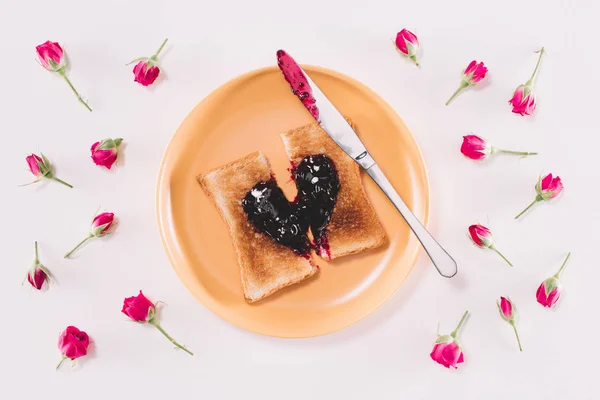 Vista dall'alto del pane tostato con marmellata e coltello su piatto giallo isolato su bianco, concetto di giorno di San Valentino — Foto stock