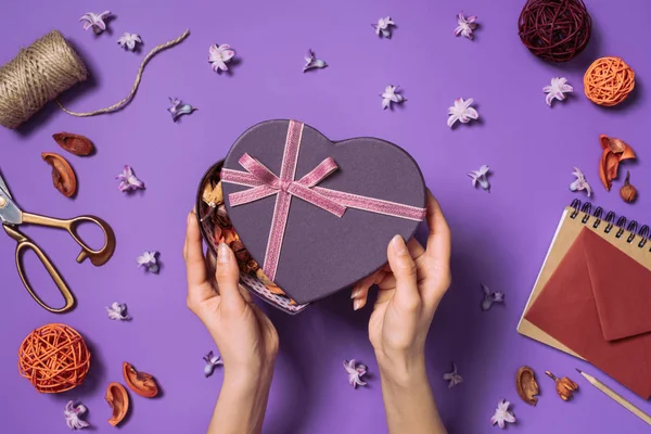 Cropped shot of woman opening heart shaped gift isolated on purple — Stock Photo