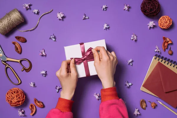 Обрізаний знімок жінки, що відкриває подарунок ізольовано на фіолетовому — стокове фото