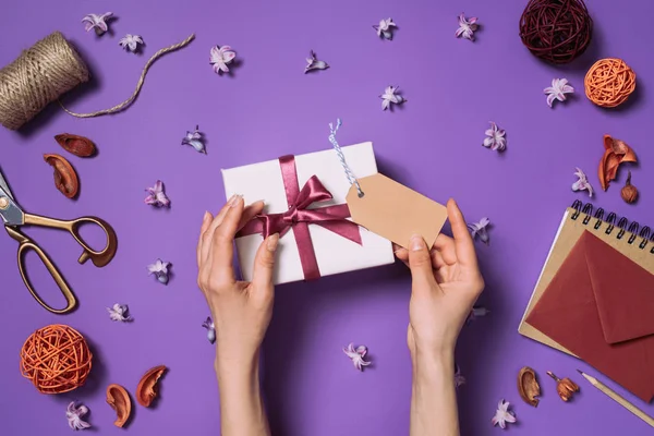 Частковий вид жінки, що тримає подарунок з картою ізольовано на фіолетовому — стокове фото