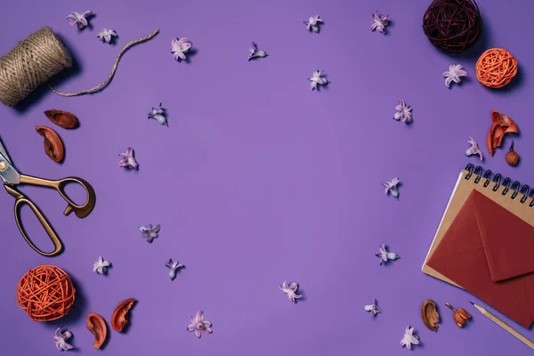 Плоский лежал с организованными цветами, конверт, ножницы и веревки для украшения изолированы на фиолетовый — стоковое фото