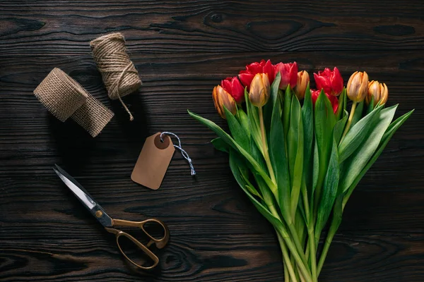Vue de dessus des tulipes disposées, corde, ciseaux et ruban pour la décoration sur la surface en bois — Photo de stock