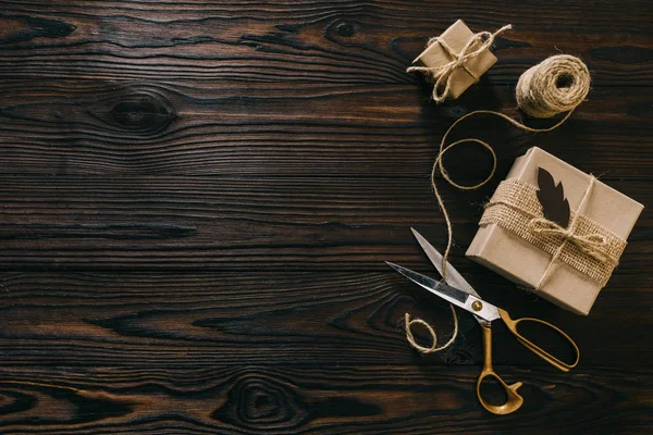 Flat lay with wrapped presents, rope and scissors on wooden surface — Stock Photo