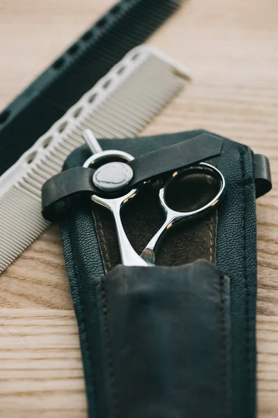 Close up view of scissors and combs for hairstyling on wooden tabletop — Stock Photo