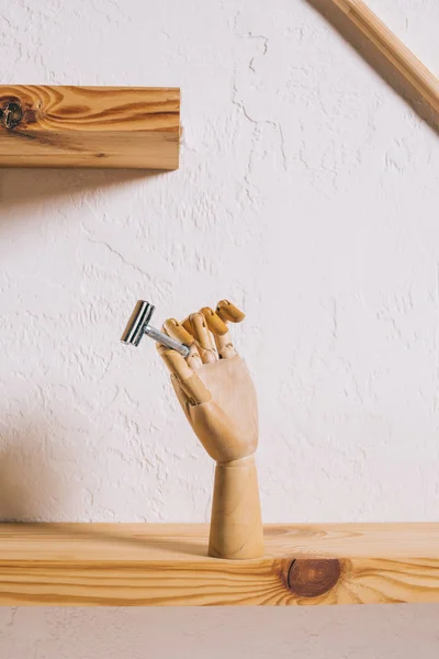 Close up view of decorative wooden hand with blade on shelf — Stock Photo