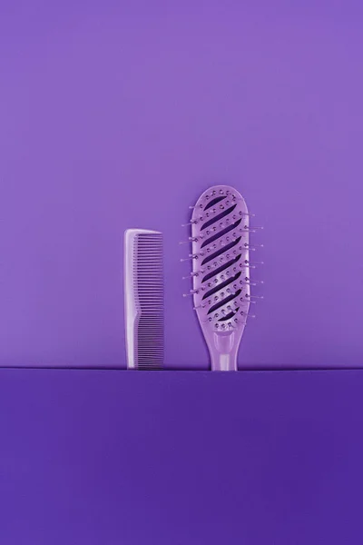 Vue rapprochée de la brosse à cheveux violette et peigne isolé sur violet — Photo de stock