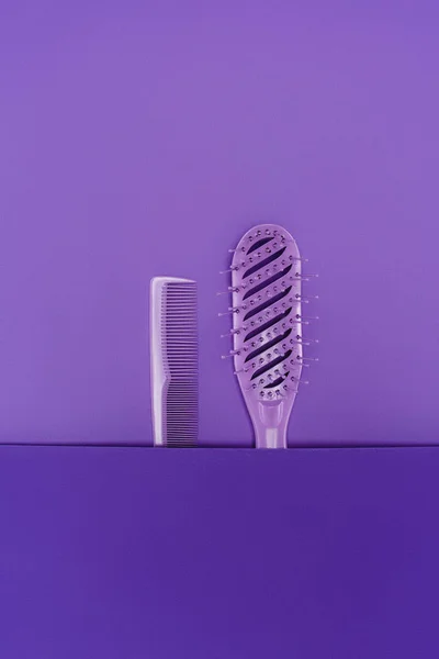 Vista de perto da escova de cabelo roxo e pente isolado em roxo — Fotografia de Stock