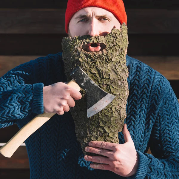 Retrato de hombre con barba hecha de corteza de madera y hacha en la mano al aire libre - foto de stock