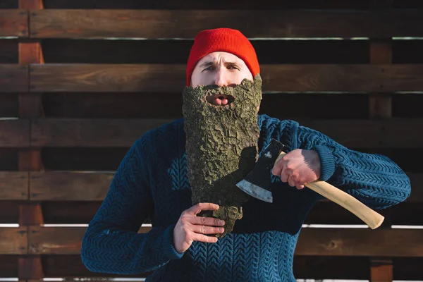 Ritratto dell'uomo con la barba fatta di corteccia di legno e ascia in mano guardando la macchina fotografica all'aperto — Foto stock