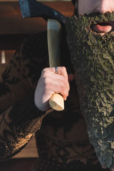 Plan recadré de l'homme avec barbe en écorce de bois et hache à la main à l'extérieur — Photo de stock