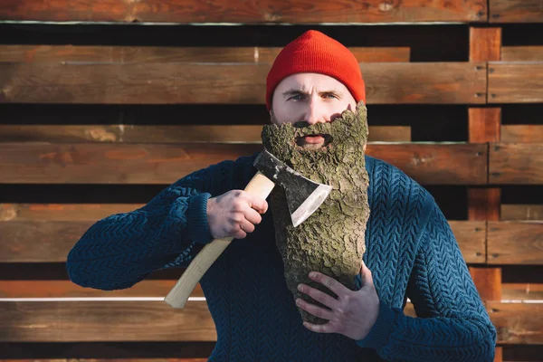 Junger Mann mit Bart aus Holzrinde und Axt in der Hand im Freien — Stockfoto