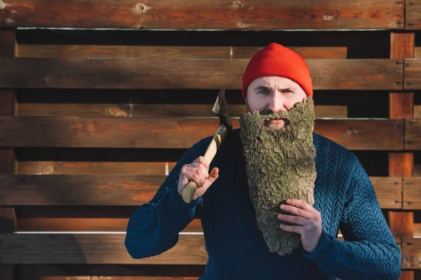 Junger Mann mit Bart aus Holzrinde und Axt in der Hand im Freien — Stockfoto