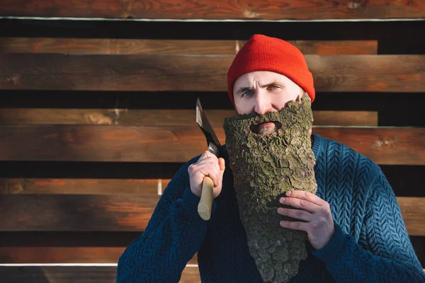Retrato de hombre con barba hecha de corteza de madera y hacha en la mano al aire libre - foto de stock