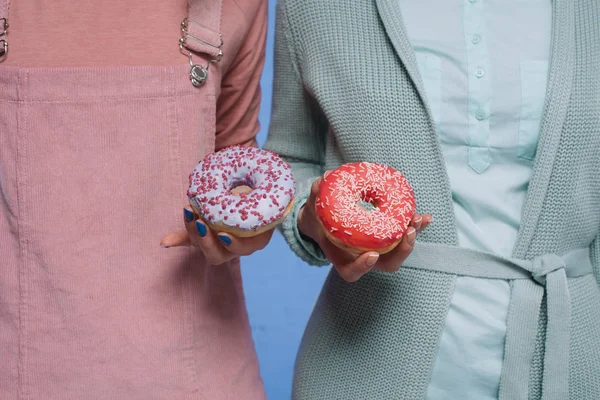 Tiro recortado de mulheres segurando donuts envidraçados — Fotografia de Stock
