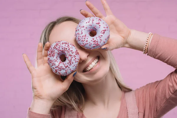 Verspielte junge Frau bedeckt Augen mit Donuts — Stockfoto