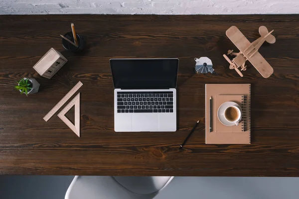 Вид зверху на ноутбук з порожнім екраном та офісними приладдям на дерев'яному столі — стокове фото